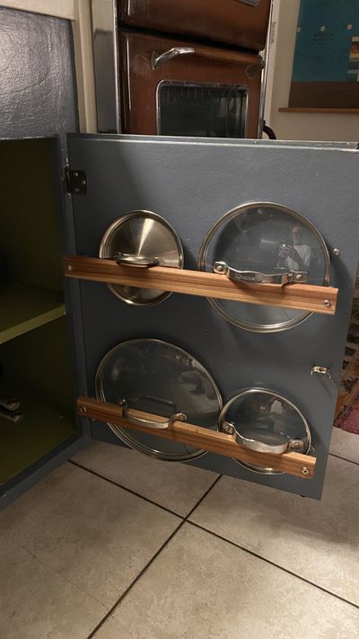 Custom pot lid storage rack with wood rails inside kitchen cabinet